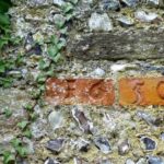 The date 1650 carved into bricks in the west side of the churchyard.